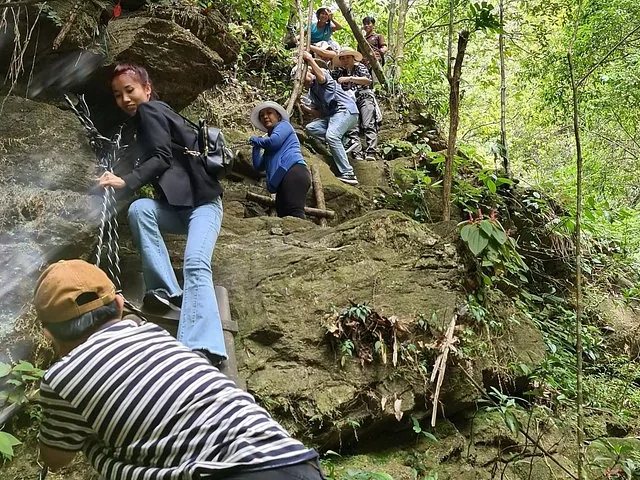 Group of tourists climbing up steep rocks in Bach Ma National Park